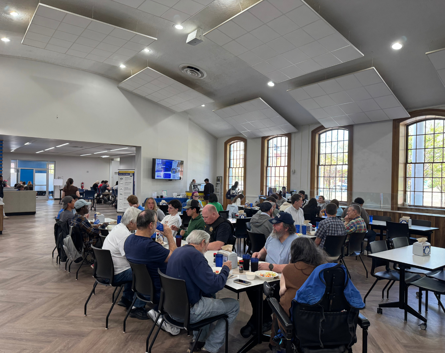 Students and community members at a table in a dining hall.
